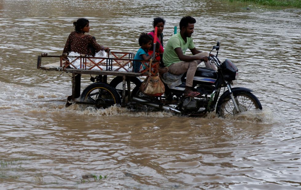 A family crosses a flooded street after heavy rains in Ahmedabad, India, August 28, 2024.