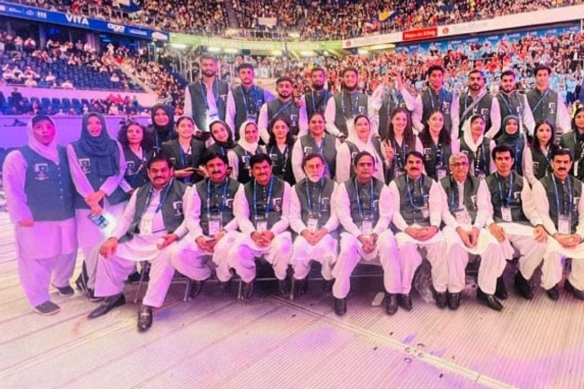 A large group wearing matching attire at an indoor stadium event, with a crowd in the background.