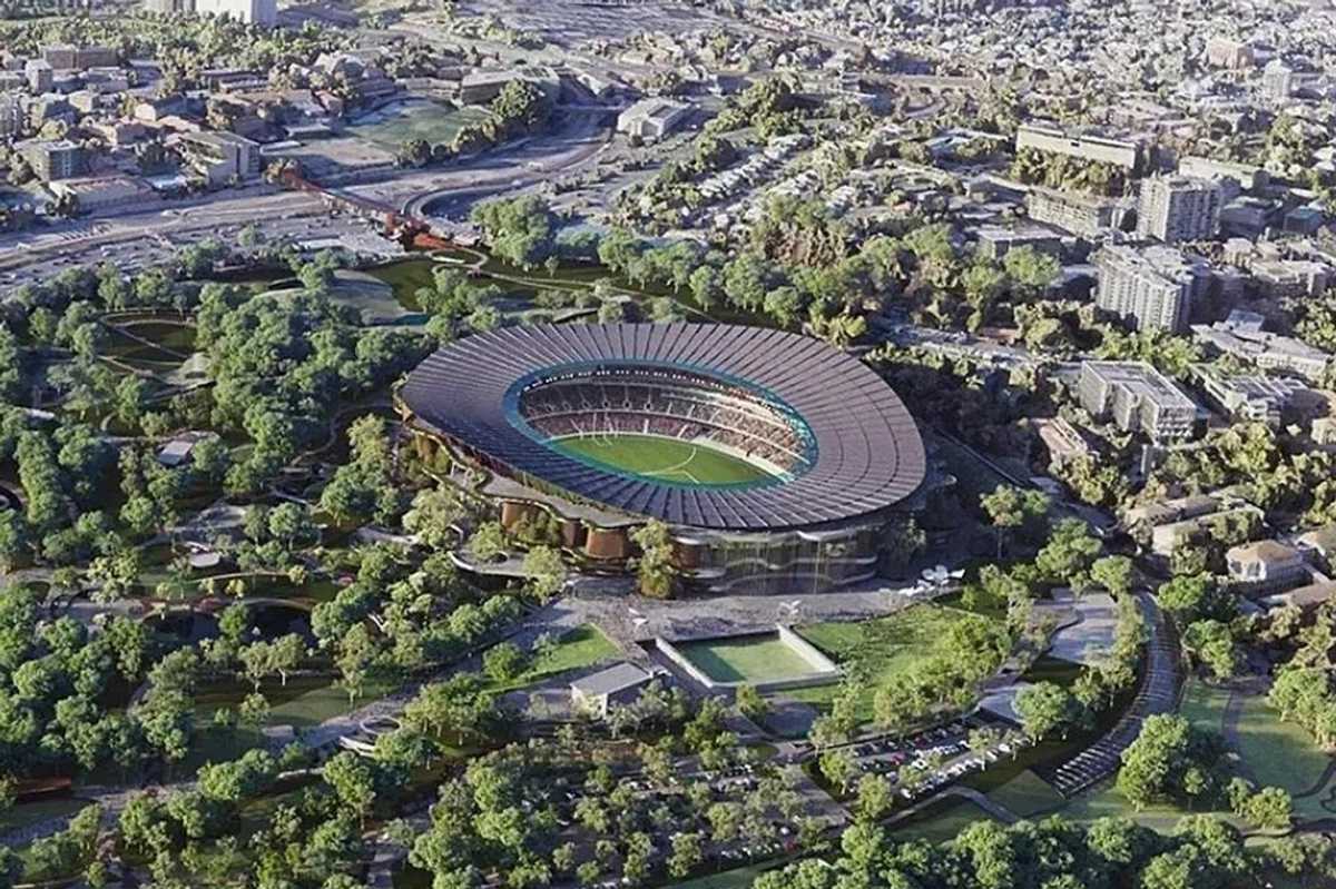 Aerial view of a large stadium amidst greenery and surrounding urban area.