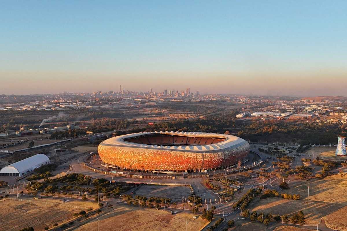 Aerial view of a large stadium in a city landscape at sunset.