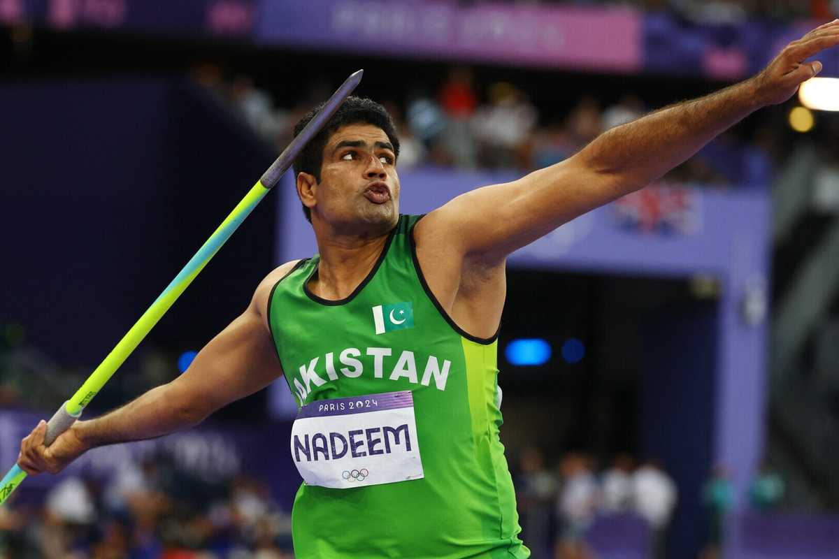 Athlete in green prepares to throw a javelin at a sports event.