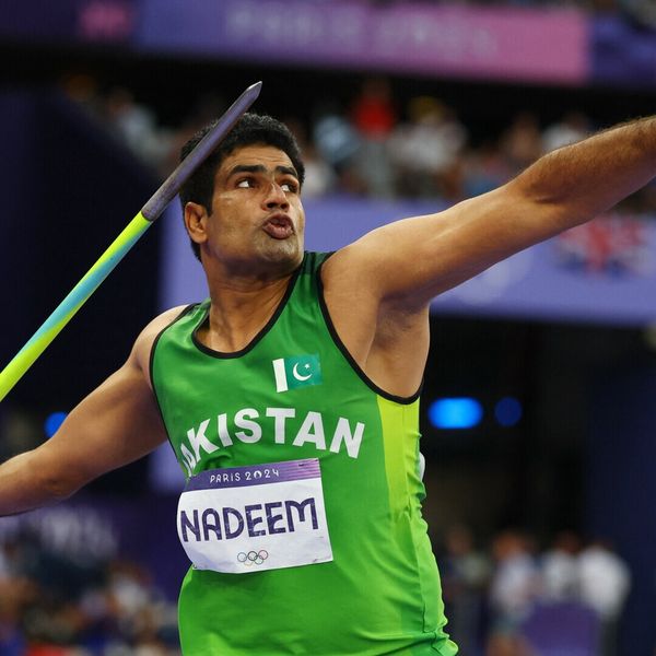 Athlete in green prepares to throw a javelin at a sports event.