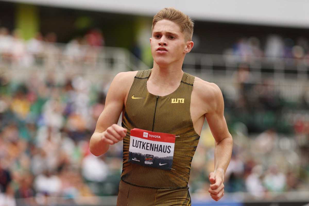 Athlete running in a striped uniform at a track event.