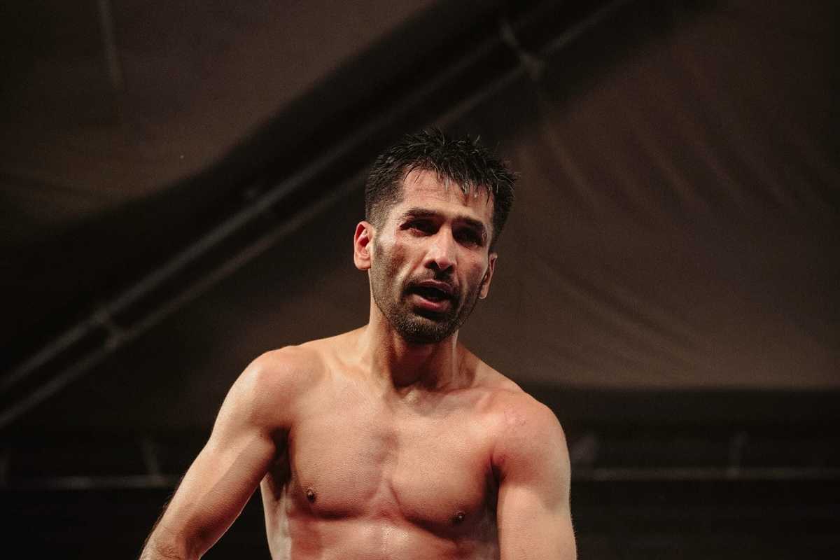Boxer with a focused expression in a dimly lit arena.