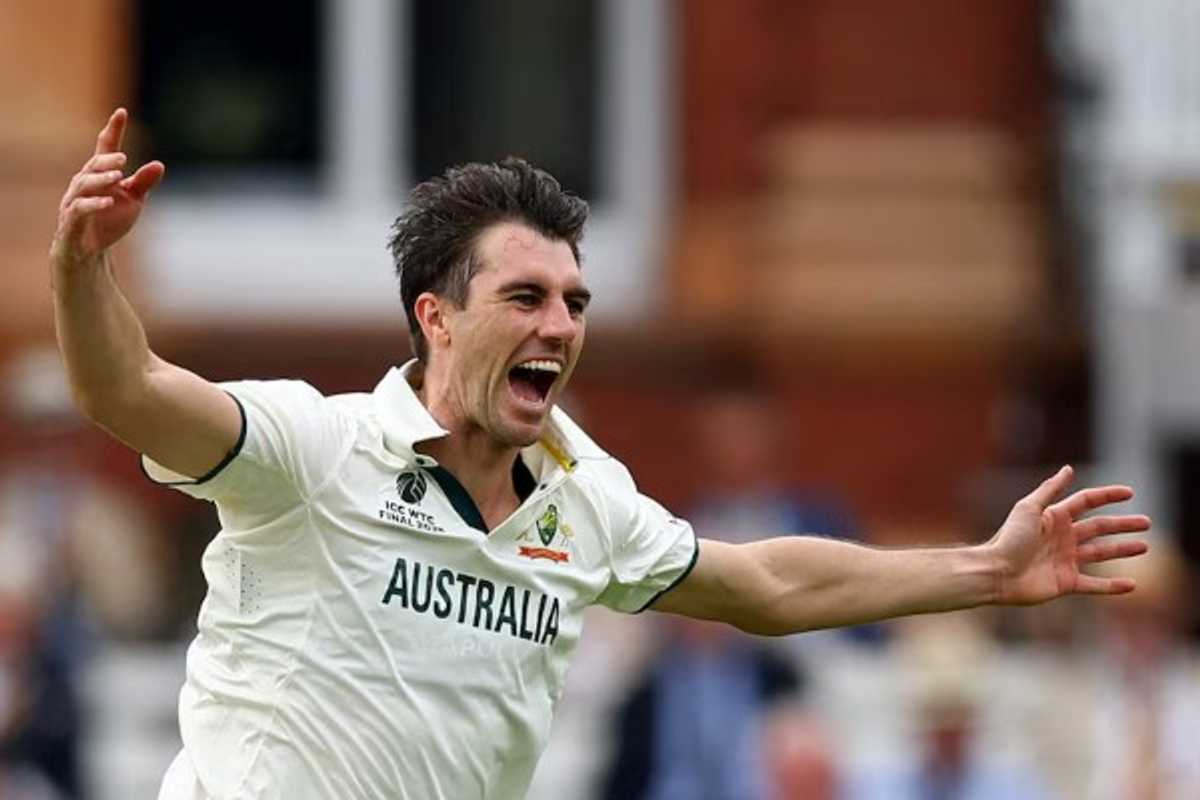 Cricket player in Australian kit celebrates with arms wide open, expressing excitement.