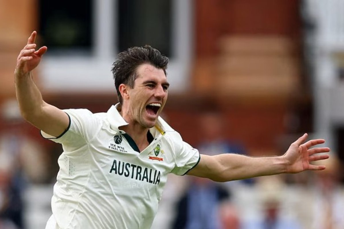Cricket player in Australian kit celebrates with arms wide open, expressing excitement.
