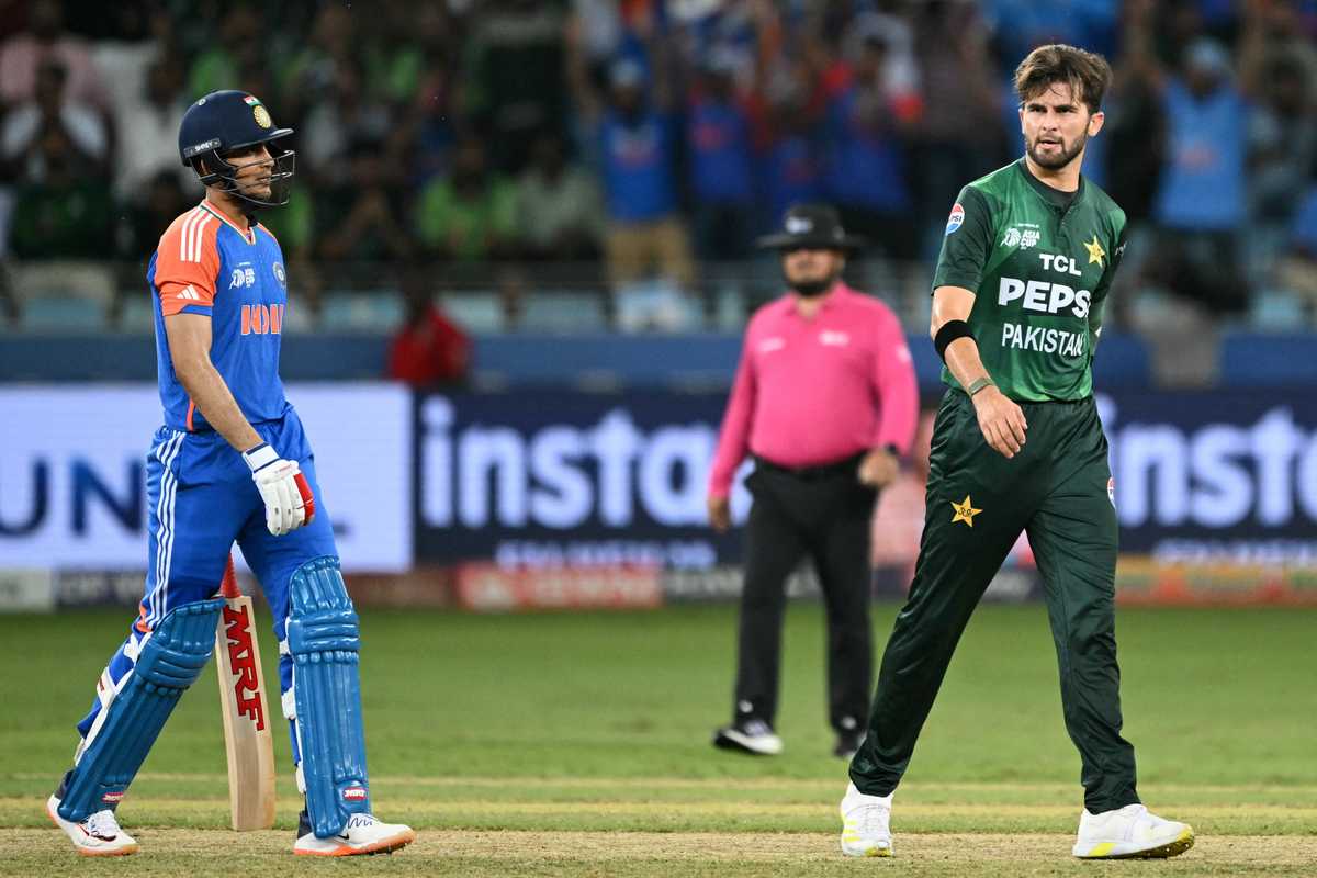 Cricket players from India and Pakistan on the field with an umpire in the background.
