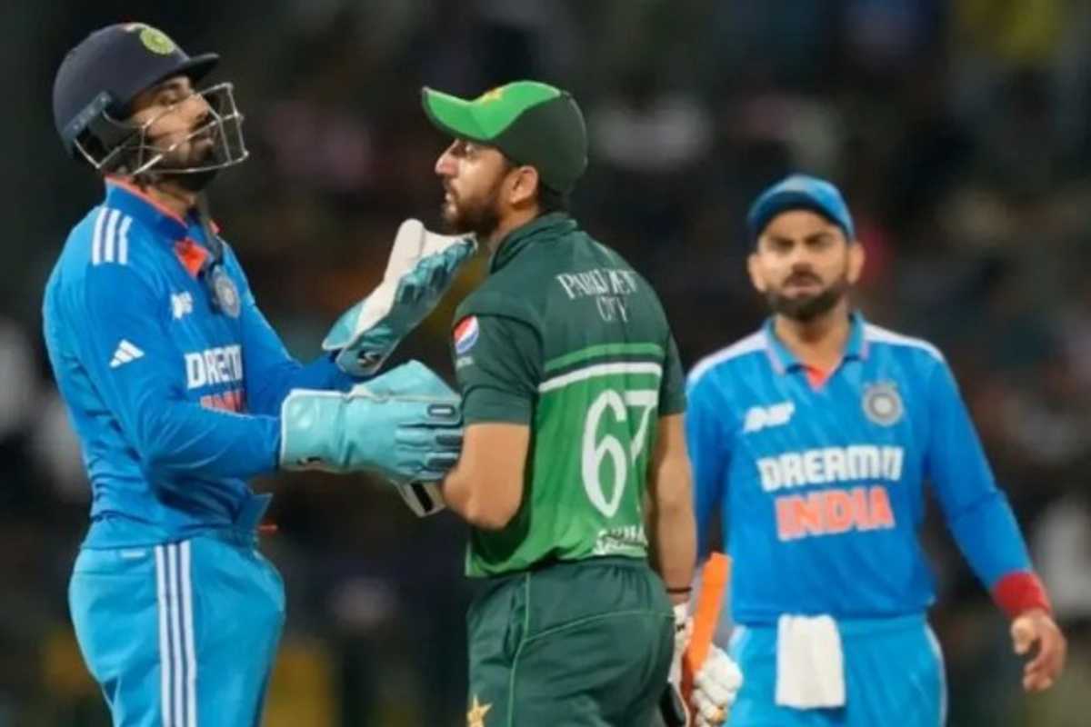 Cricketer gestures towards opponent wearing blue during a match, another player in background.