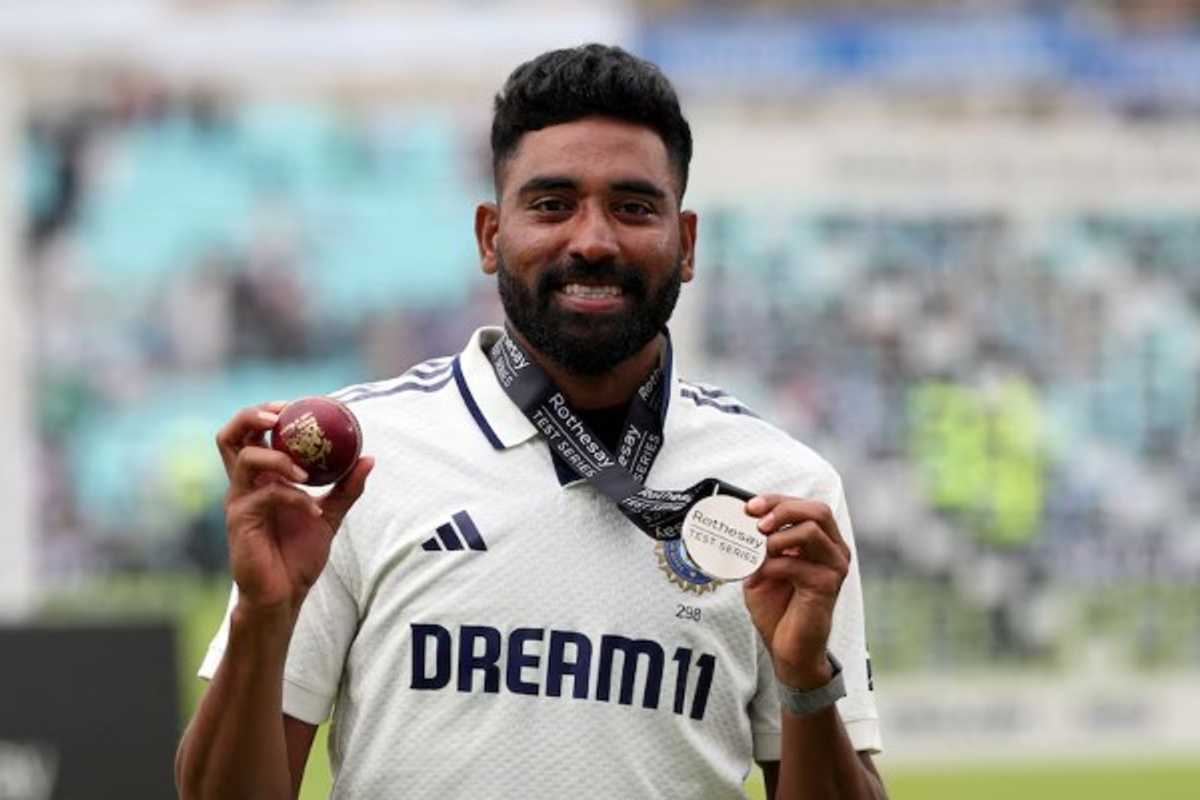 Cricketer holding a red ball and silver medal, wearing a white jersey.