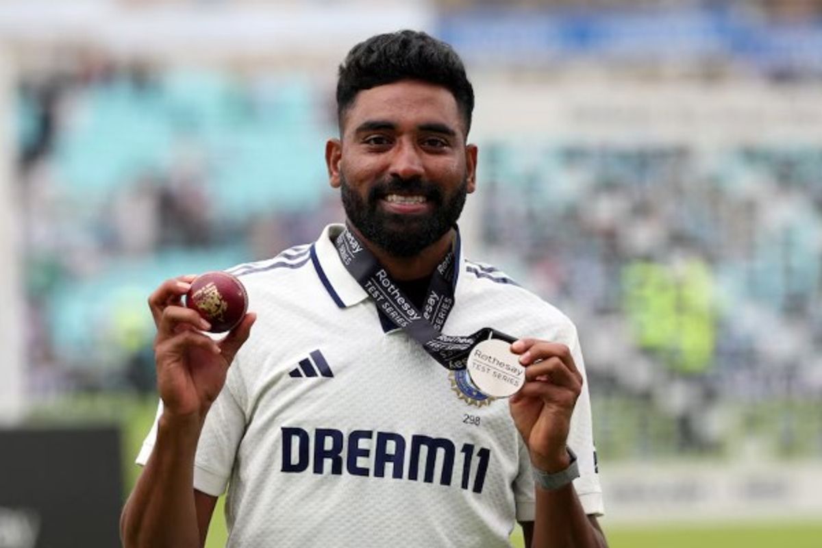 Cricketer holding a red ball and silver medal, wearing a white jersey.