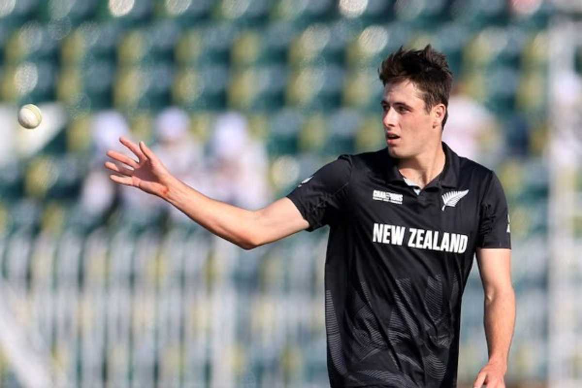 Cricketer in New Zealand uniform tosses a ball on the field.