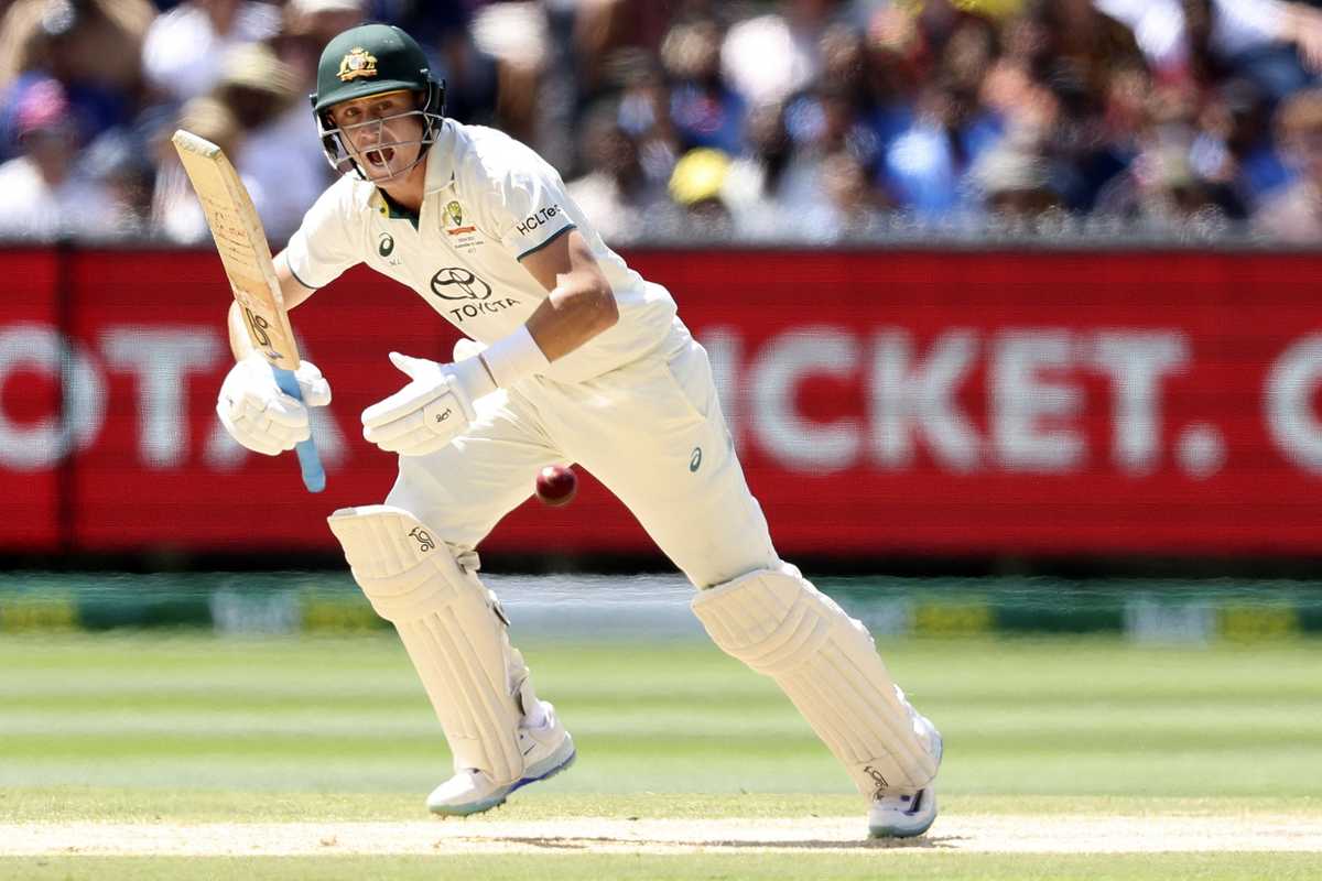 Cricketer in white uniform batting during a match, red ball in motion.
