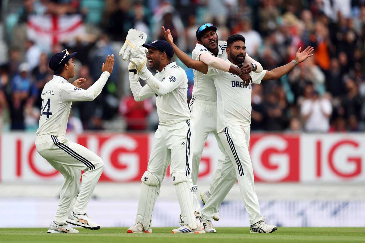 Cricketers celebrating a wicket on the field with joyous expressions and gestures.