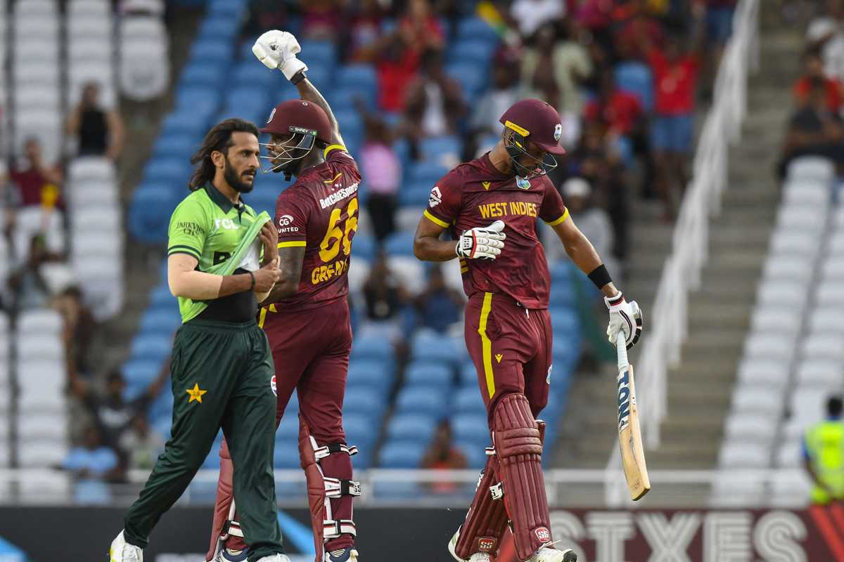 Cricketers on field, one West Indies player raising his fist in celebration, facing a Pakistani player.