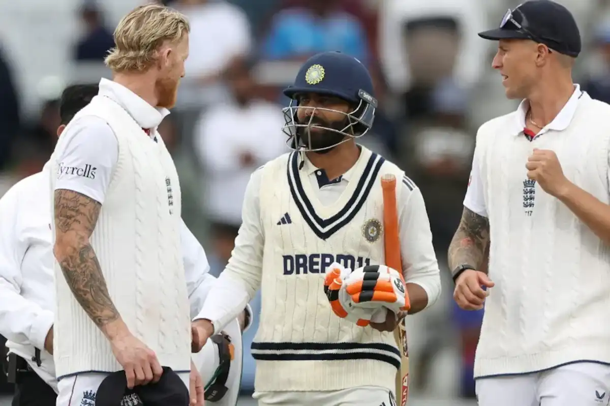 Cricketers smiling and talking on the field, one holding a bat.