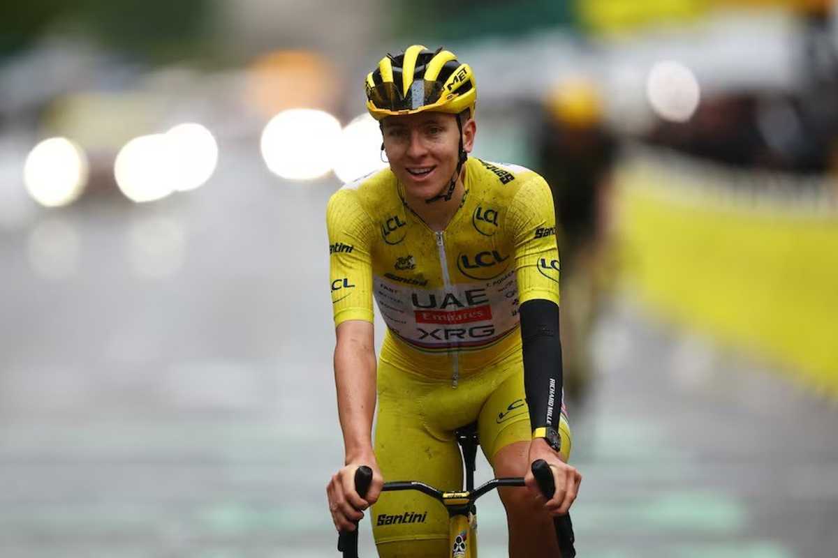 Cyclist in yellow gear rides on a wet road during a race.