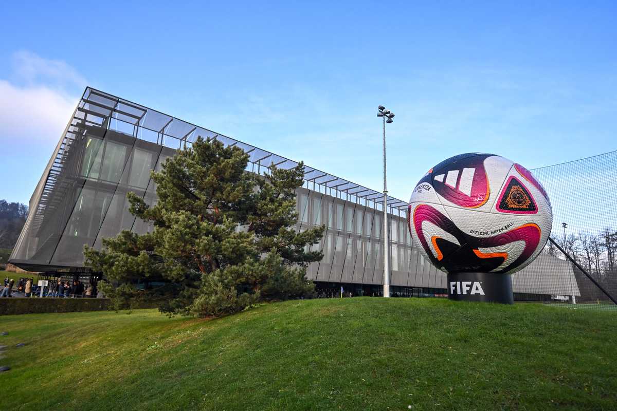 Giant FIFA soccer ball in front of a modern glass building, with a clear blue sky.