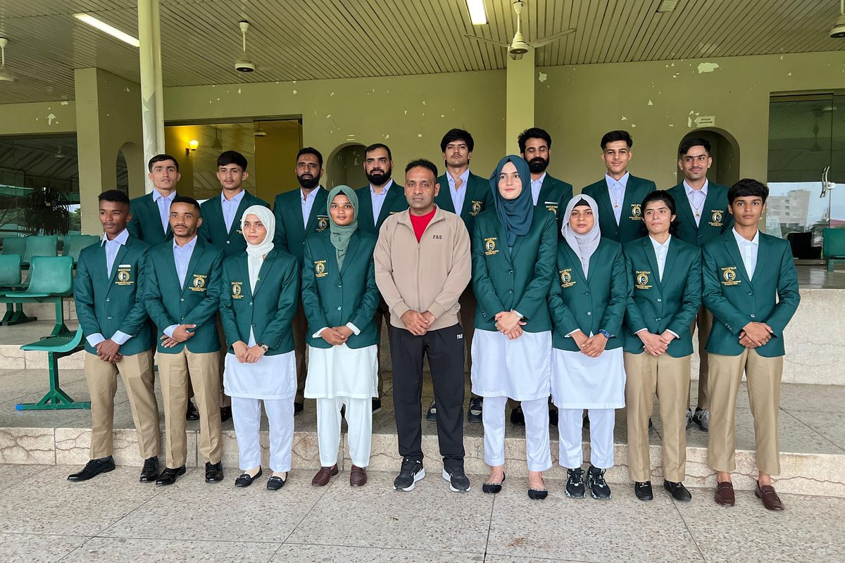 Group of students in green blazers posing in front of a building.