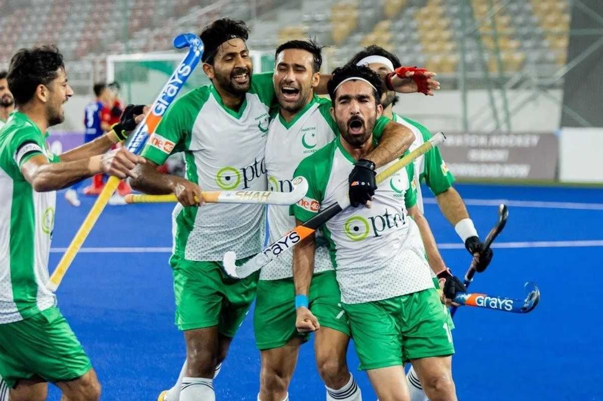 Hockey players in green jerseys celebrate on a blue field.