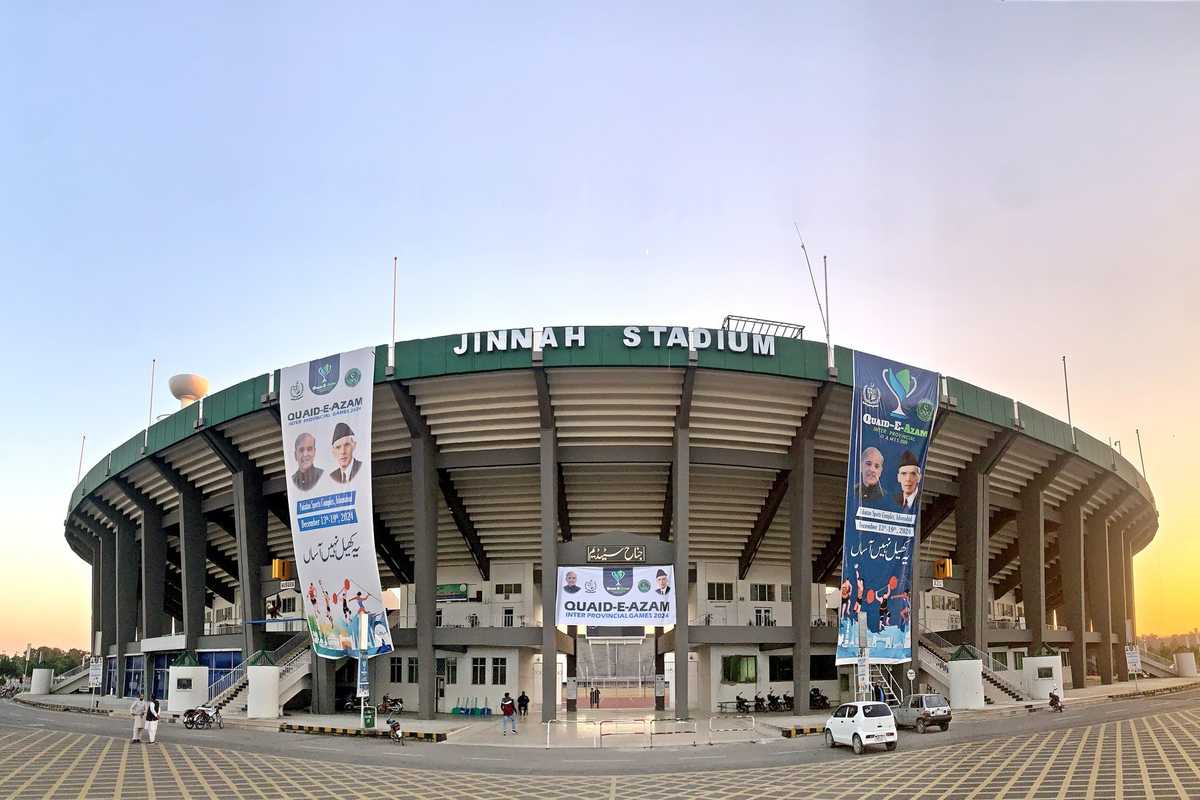 Jinnah Stadium exterior with banners at sunset, featuring a wide-open plaza in front.