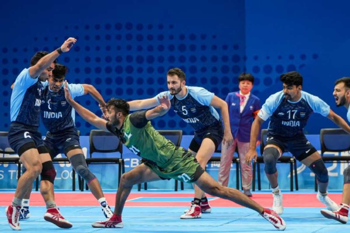 Kabaddi match action; players in mid-movement on a blue court.