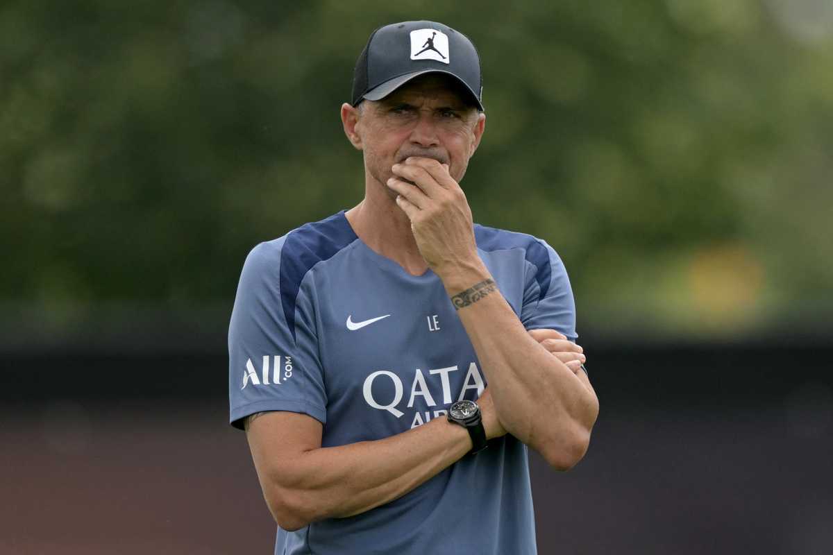 Man in sportswear and cap, pondering with hand on chin.