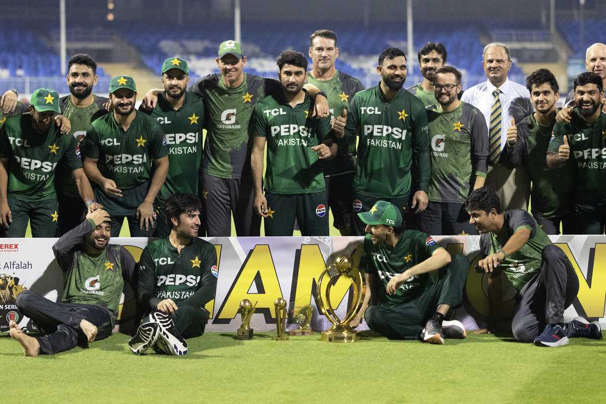 Pakistan cricket team celebrates with trophy on the field.