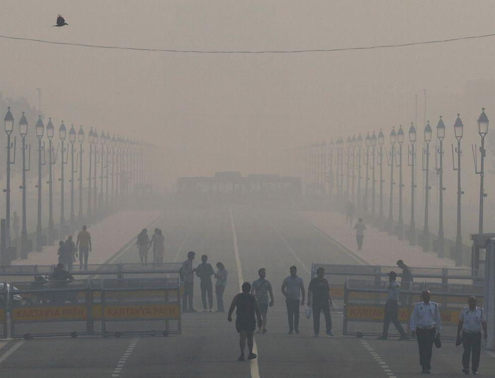 People walk on 'Kartavya Path' amidst the morning smog in New Delhi, India,