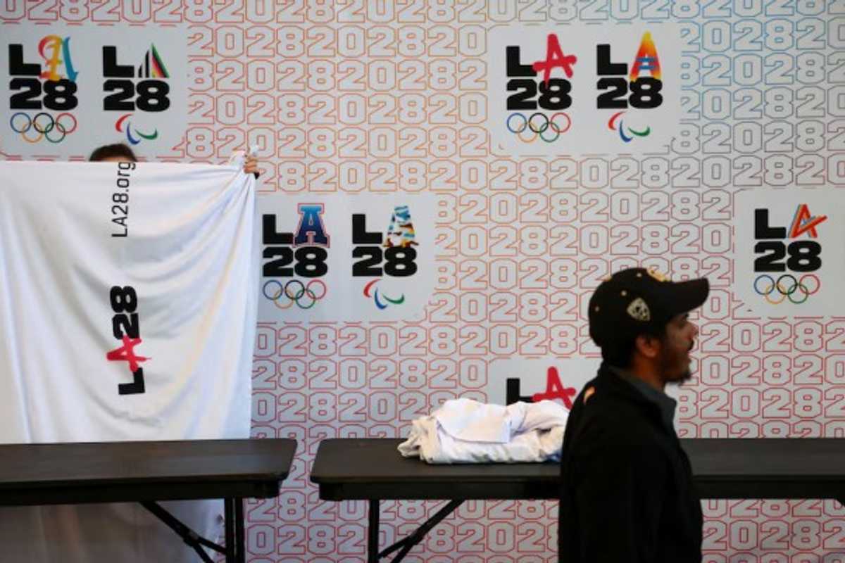 Person holding LA28 banner at the 2028 Olympics display stand.