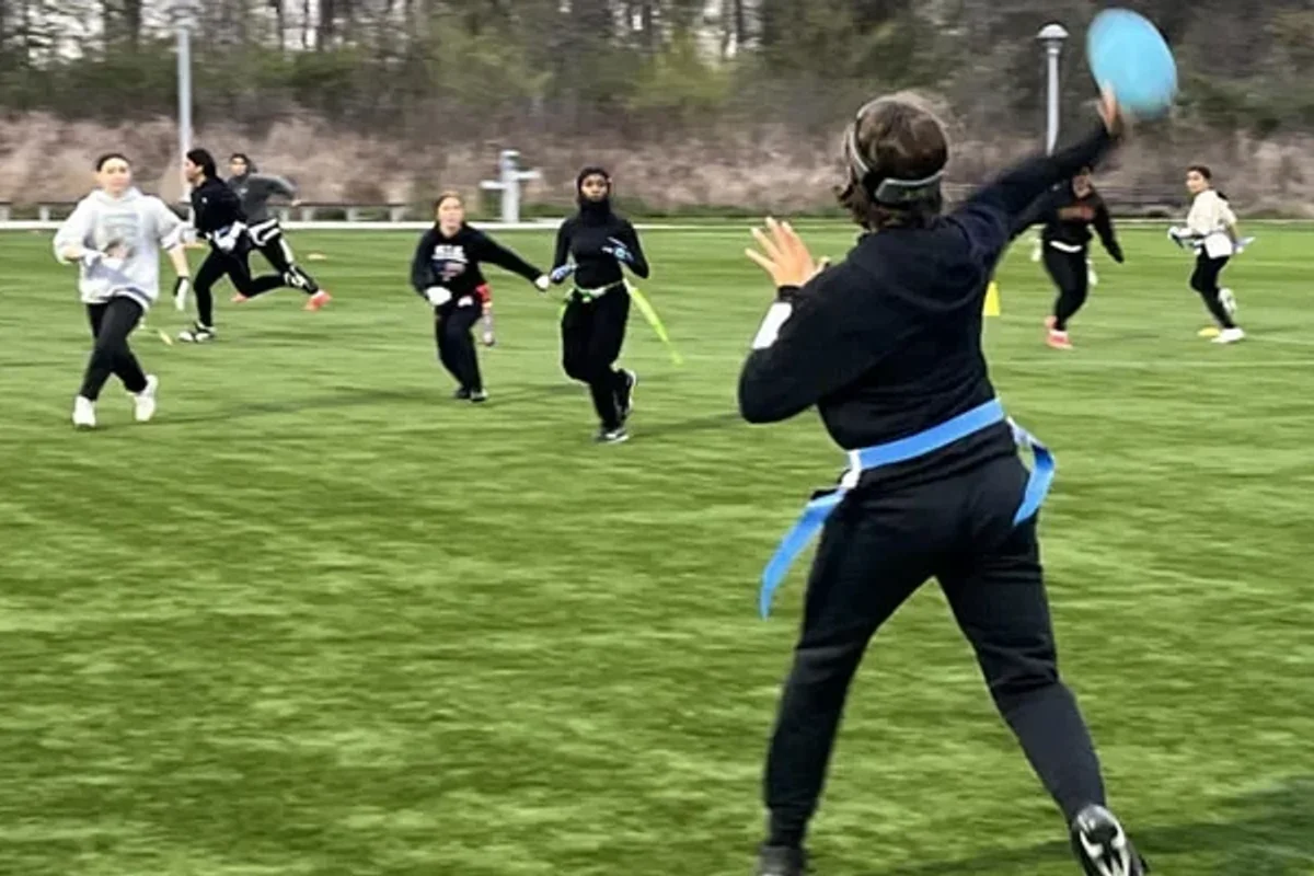 Person throwing a football during a women's flag football game.
