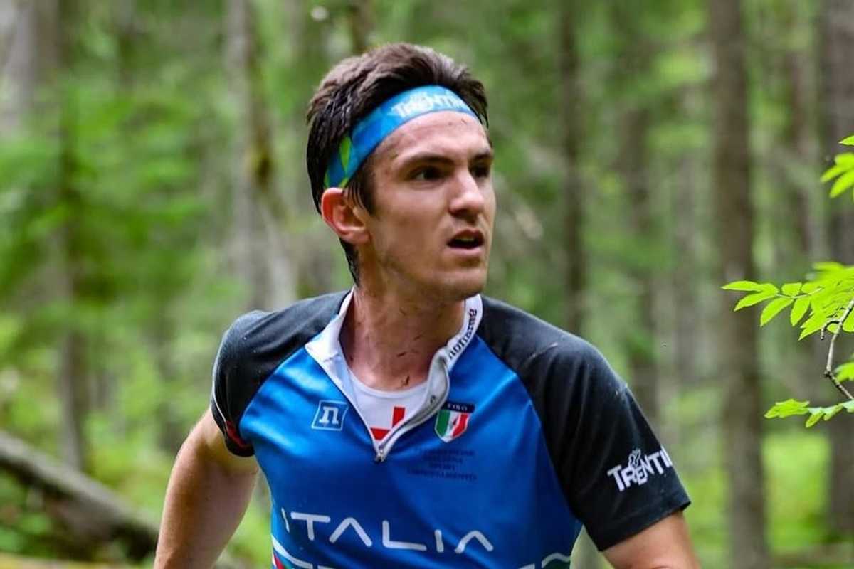 Runner in a blue jersey in a wooded area, looking focused.