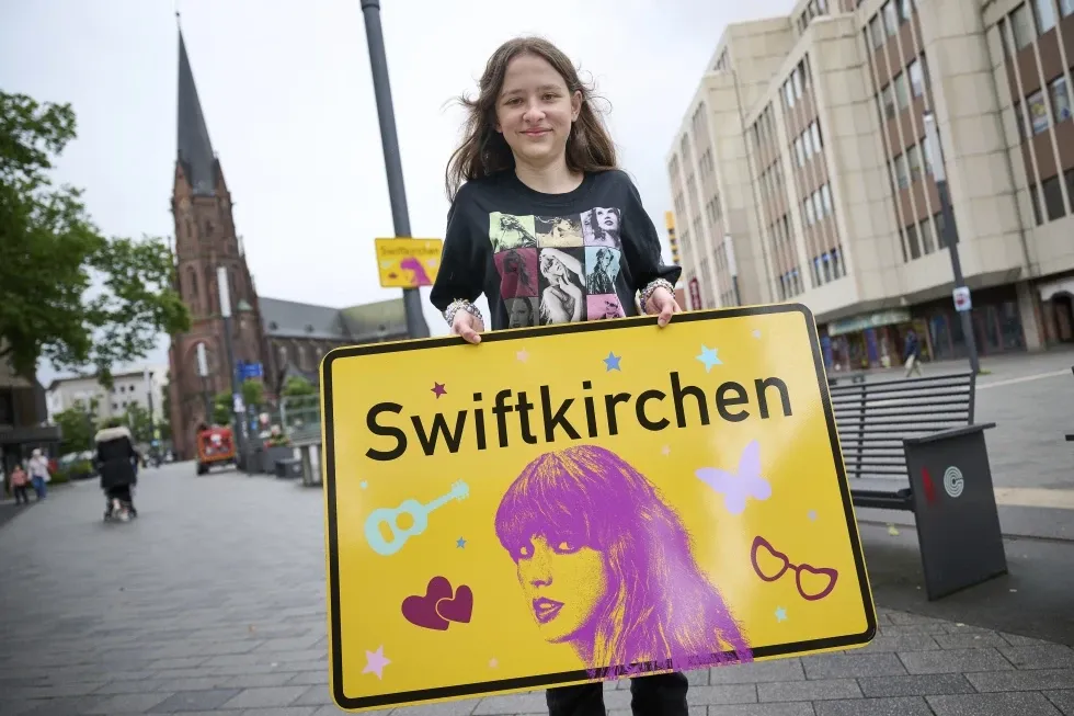Schoolgirl Aleshanee Westhoff shows a \u201cSwiftkirchen\u201d town sign in honor of musician Taylor Swift in Gelsenkirchen, Germany