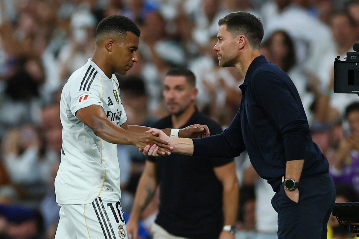 Soccer player and coach exchange a handshake on the field.