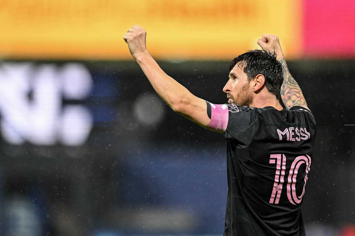 Soccer player in black jersey with "10" raises arms in celebration.