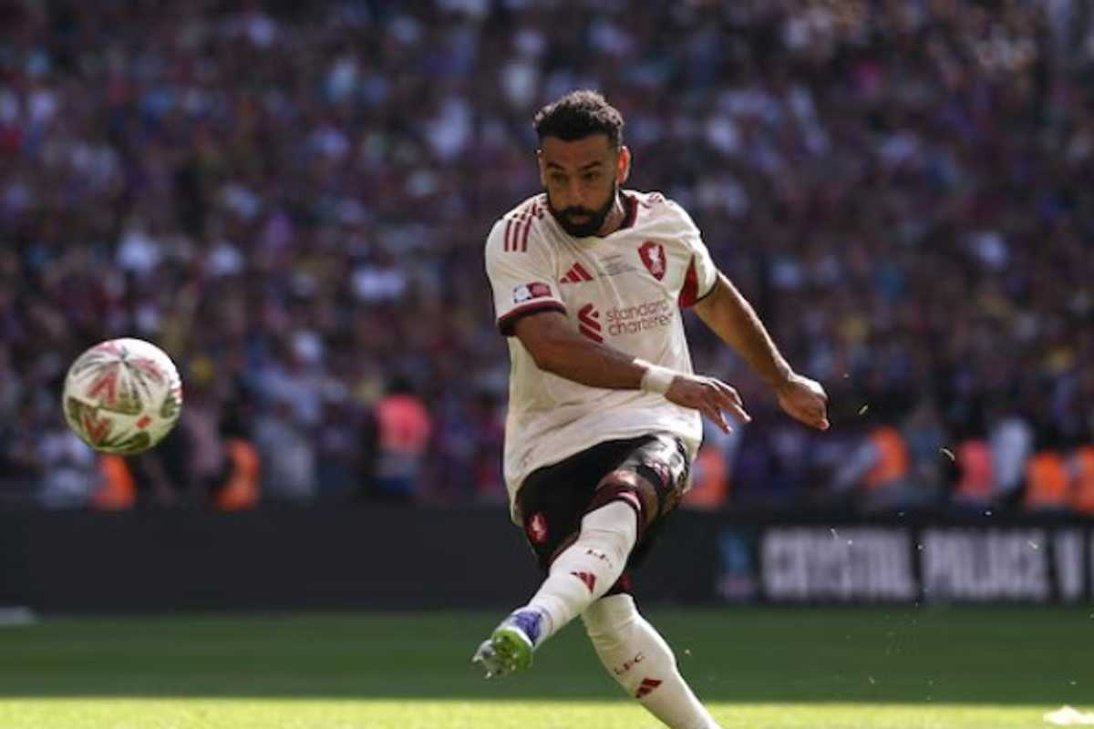 Soccer player in white jersey striking a ball on the field during a match.