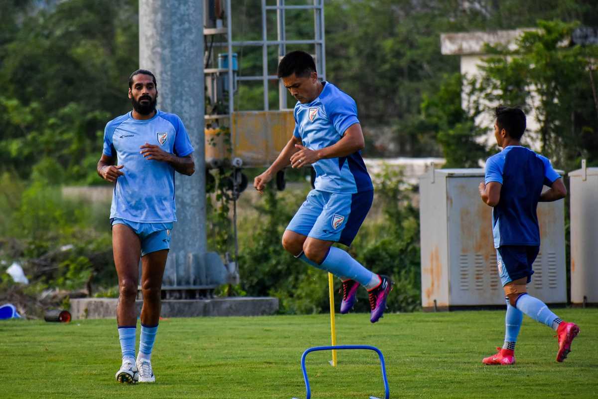 Soccer players in blue jerseys doing training drills on a grassy field.