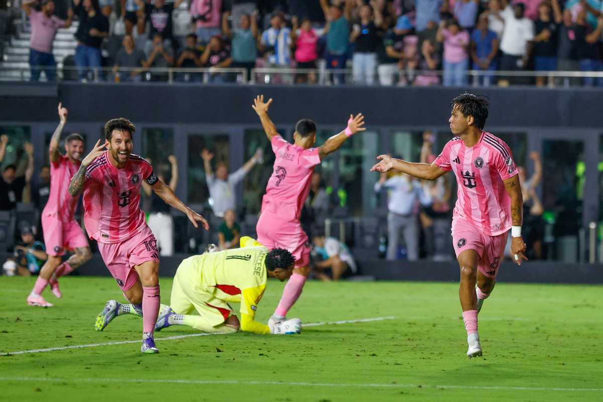 Soccer players in pink jerseys celebrate a goal on the field.