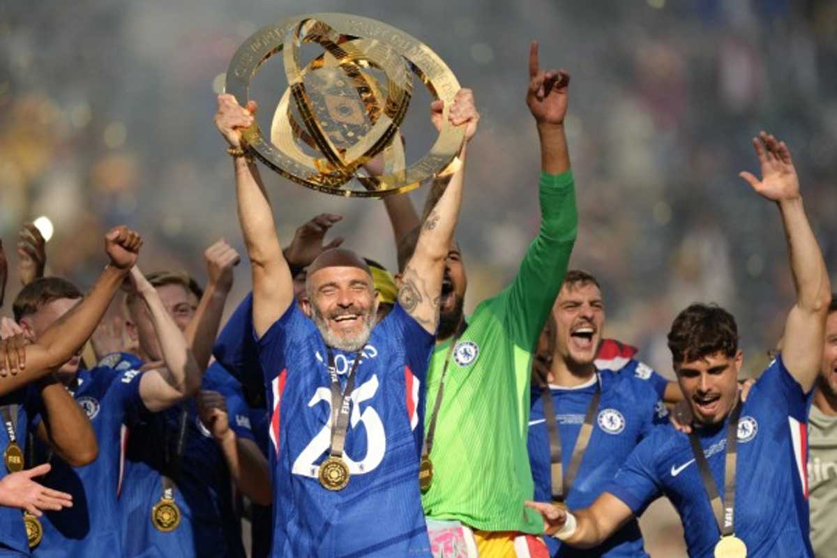 Soccer team celebrates, player holds a championship trophy aloft, wearing medals.