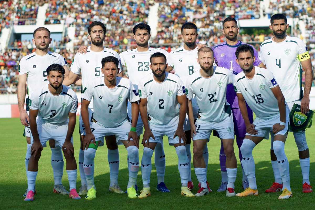 Soccer team in white jerseys posing for a group photo on a crowded field.