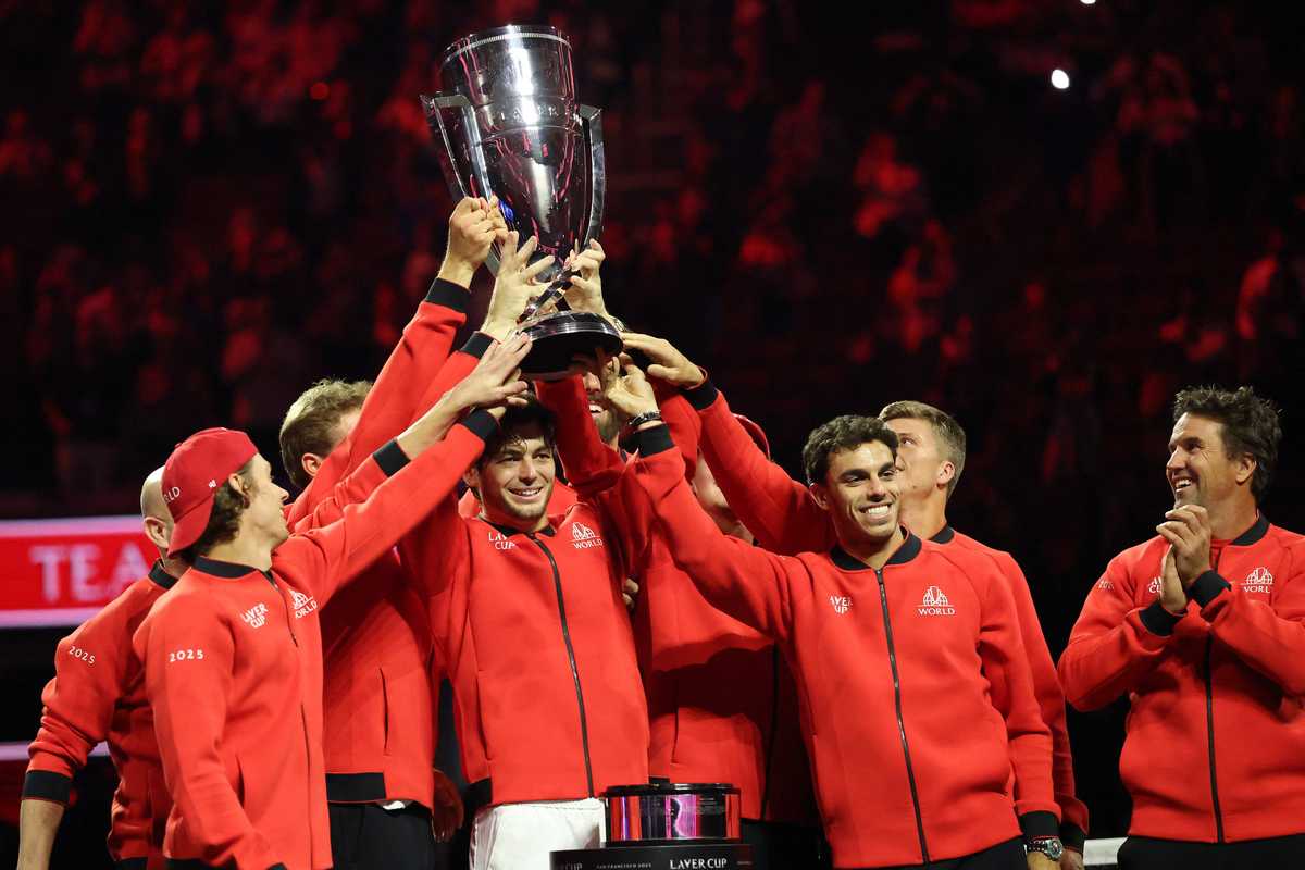 Team in red jackets celebrating with a trophy on stage at the Laver Cup.