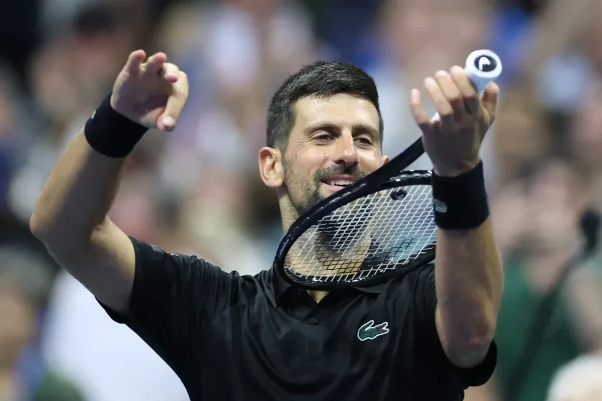 Tennis player celebrates, holding a racket and ball on the court.