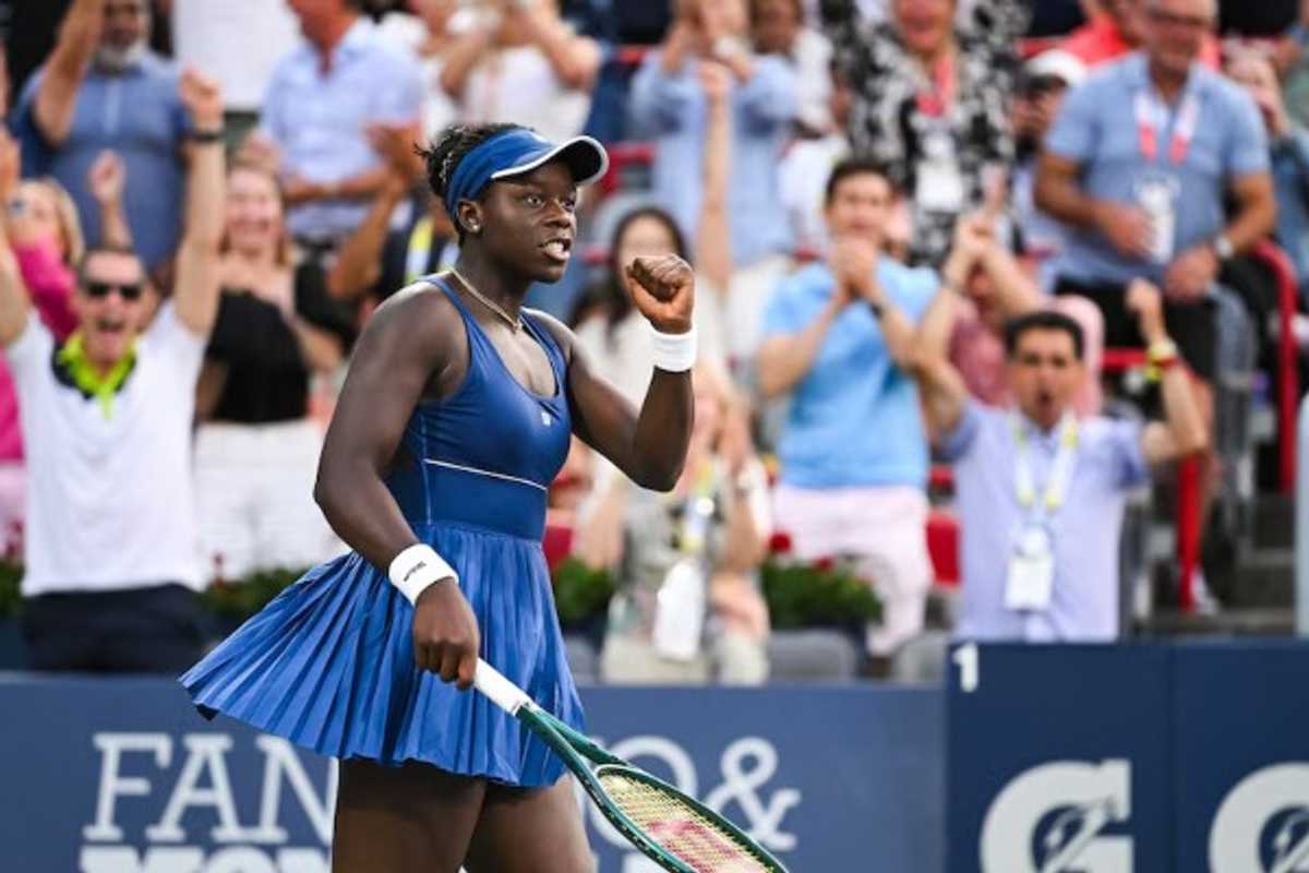 Tennis player celebrates on court as cheering crowd stands in the background.