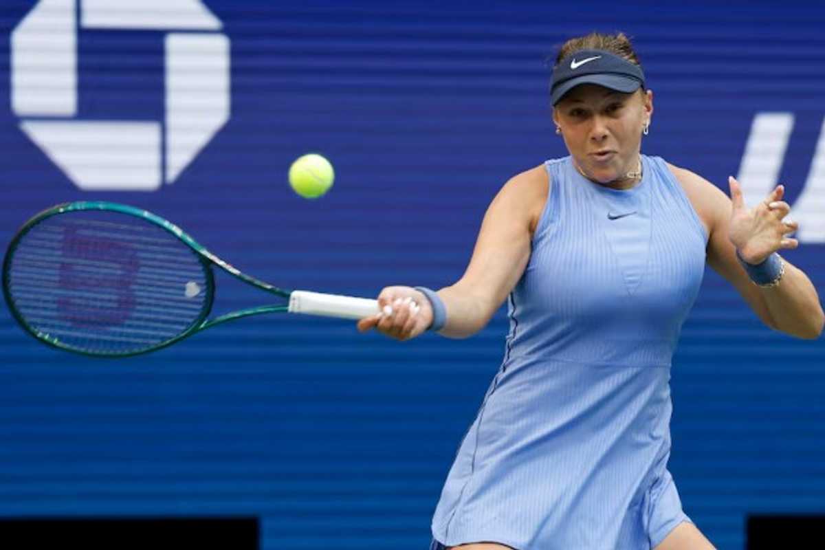 Tennis player in blue dress hitting a forehand shot during a match.