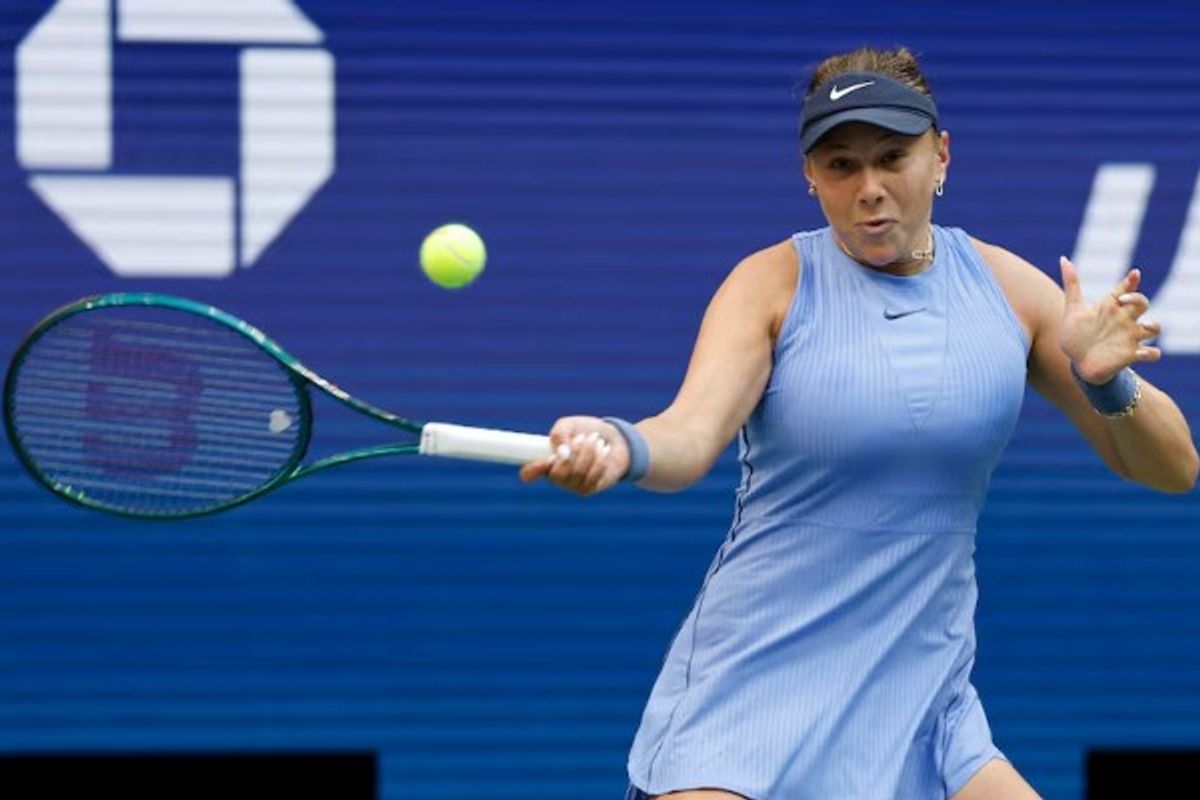 Tennis player in blue dress hitting a forehand shot during a match.