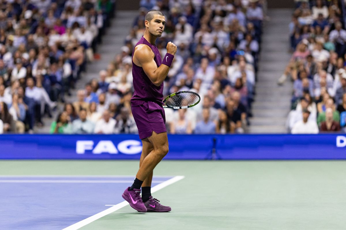 Tennis player in purple celebrates a point on a court, with a crowd in the background.
