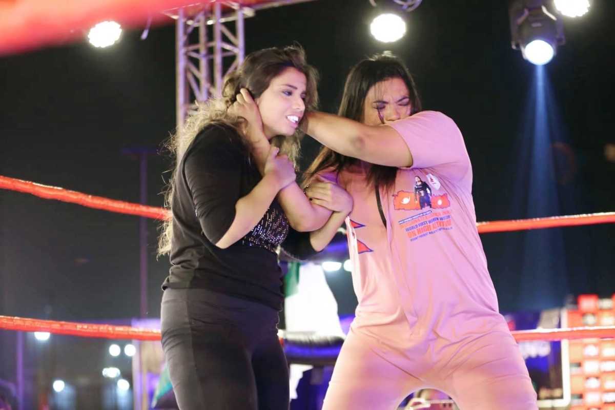 Two women wrestling in a professional ring under bright lights.