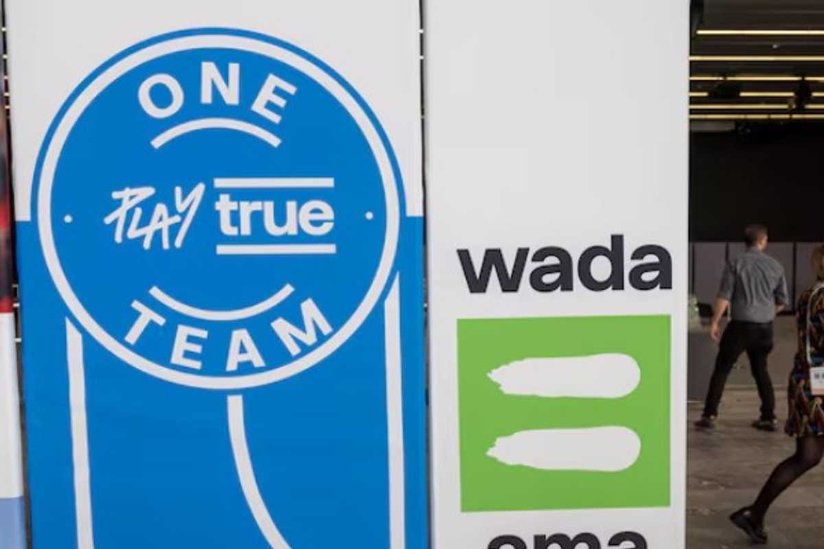 WADA "Play True" sign, people walking in a hallway in the background.