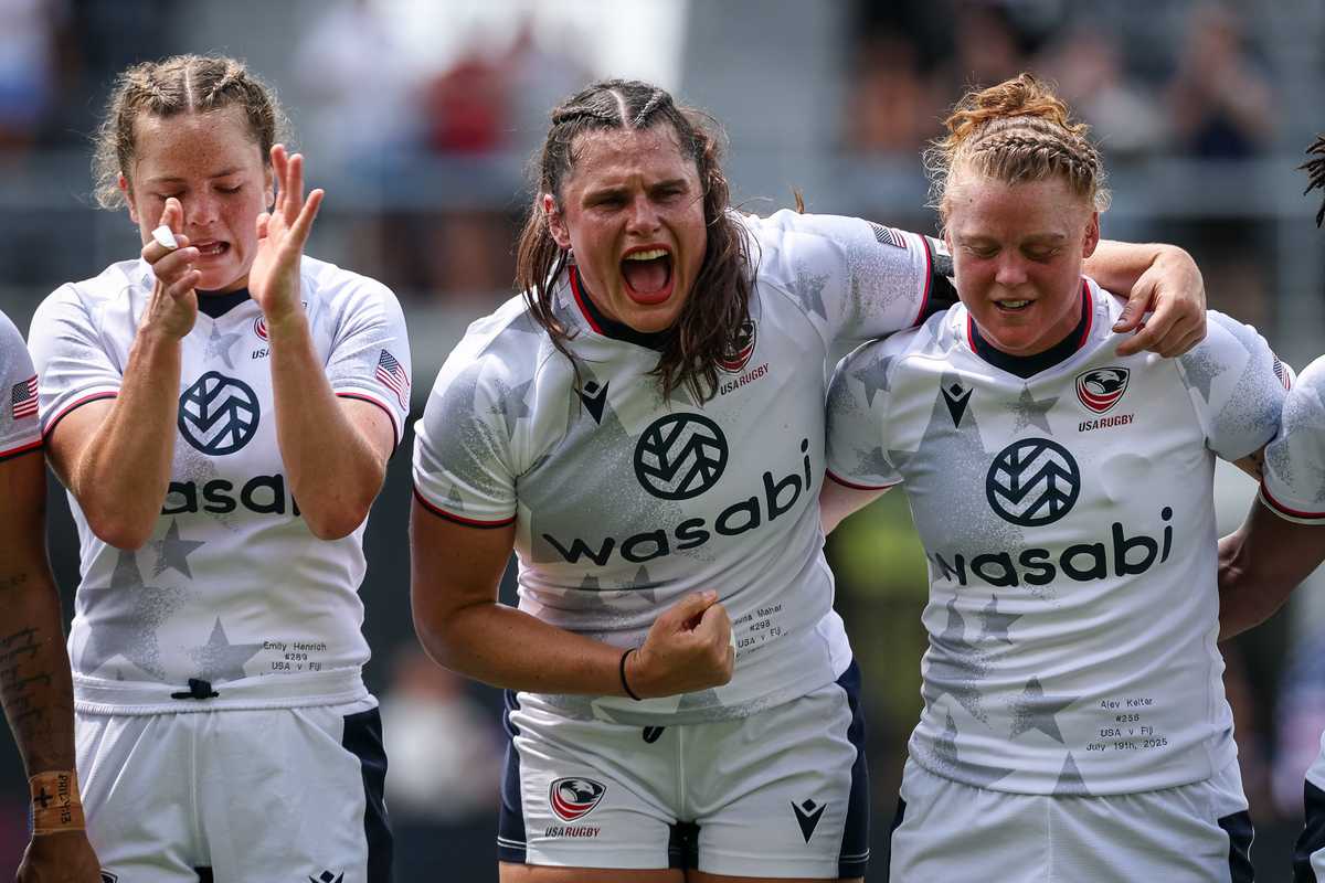 Women's rugby players celebrating energetically on the field.